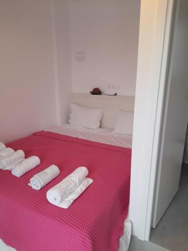 een bed met drie witte handdoeken op een roze deken bij Villa Foivos in Agios Romanos