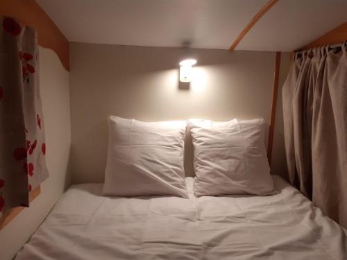 ein Bett mit weißen Laken und Kissen in einem Zimmer in der Unterkunft Véritable roulotte à la campagne in Bassillon-Vauzé