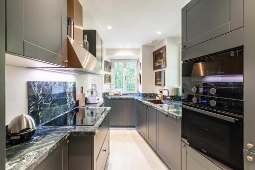 une grande cuisine avec des armoires grises et des appareils électroménagers noirs dans l'établissement Luxurious Villa with heated pool 5BR-10p - Cannes, à Cannes