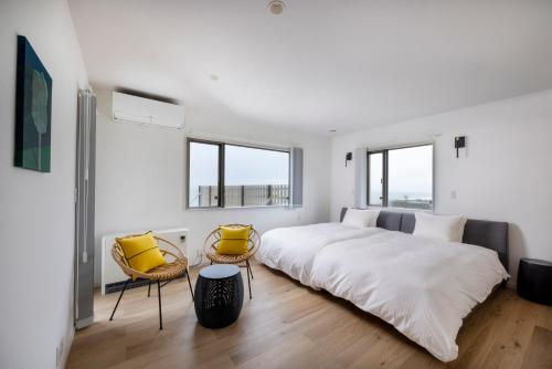 a white bedroom with a large bed and two chairs at Izumo HOTEL THE CLIFF 