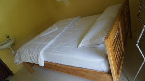 a bed with white sheets and a wooden frame at Wisma kelimutu in Ende