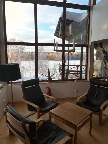 a living room with two chairs and a table and a large window at The paradise by the beach in Långviken