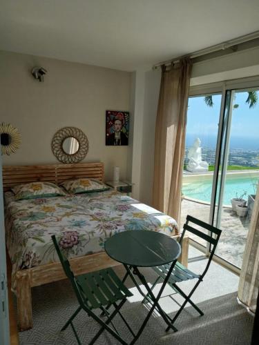 een slaapkamer met een bed en een tafel en stoelen bij Le Cocon Perché à La Possession in La Possession