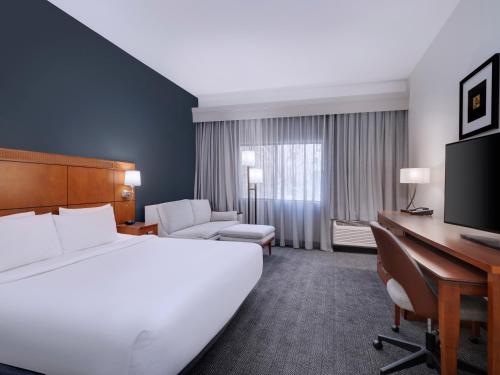 a hotel room with a large bed and a desk at Courtyard Tampa North / I-75 Fletcher in Tampa