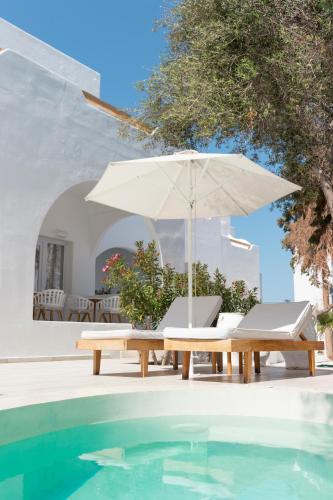a table and chairs with an umbrella next to a swimming pool at Cavo Bianco Boutique Hotel & Spa in Kamari