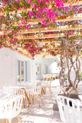 a room with white tables and chairs and pink flowers at Cavo Bianco Boutique Hotel & Spa in Kamari