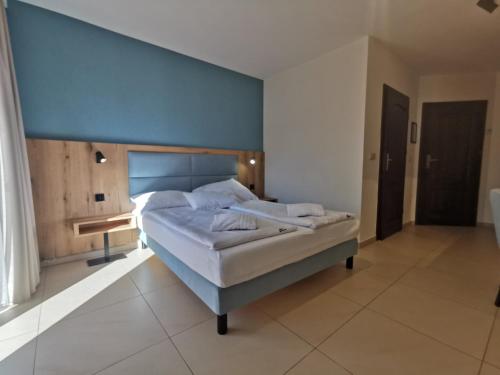 ein Schlafzimmer mit einem großen Bett mit blauer Wand in der Unterkunft Paula Wellness & SPA in Pobierowo