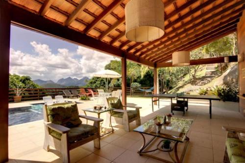 une terrasse avec des chaises et des tables, ainsi qu'une piscine. dans l'établissement Pousada Alto Itaipava, à Itaipava