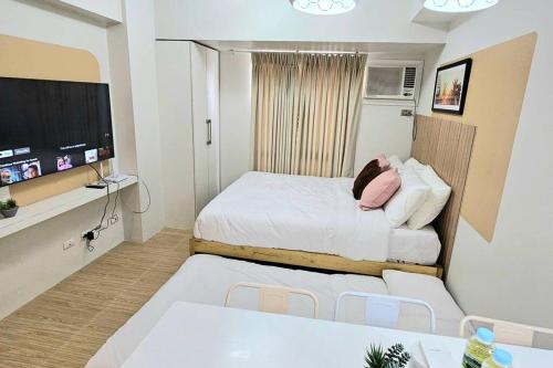 a small room with a bed and a flat screen tv at Steff's Condo 211 For 3 Pax in Cagayan de Oro