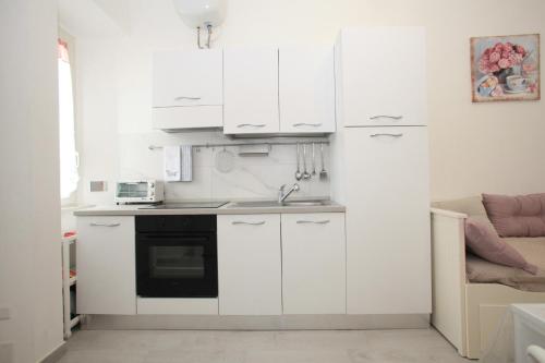 eine kleine Küche mit weißen Schränken und einem Waschbecken in der Unterkunft Brillante Appartamento di Sara in Anzio