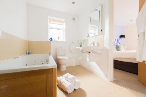 a bathroom with a sink and a toilet and a bed at Skylark sleeps 8 private Hot Tub & Dogs welcome Nr Padstow, Resort Pool Bar & Watersports in Saint Columb Major