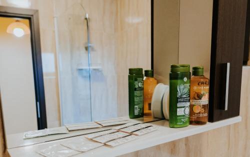 a bathroom counter with bottles of shampoo and a mirror at Carla's Studio Central Palas, airport shuttle in Iaşi