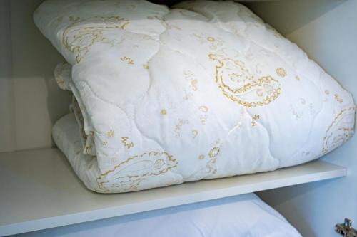a white pillow with gold embroidery sitting on a shelf at Уютная квартира-студия в старом центре города Актобе in Aktobe