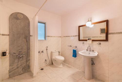 a bathroom with a shower and a toilet and a sink at SaffronStays Chikoo Wadi- 3BDR Pet-friendly Villa with Pool in Boisar in Boisar