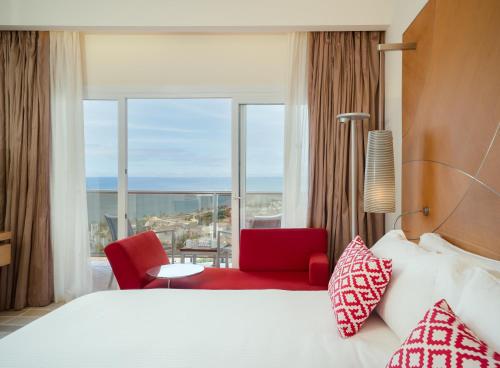 a hotel room with a bed and a red chair at Don Carlos Resort & Spa in Marbella