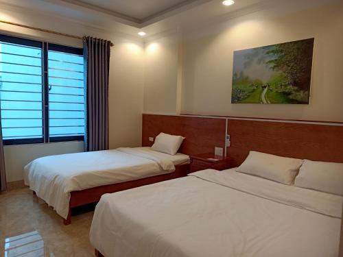 Habitación de hotel con 2 camas y ventana en Hotel trung hiếu en Ha Long