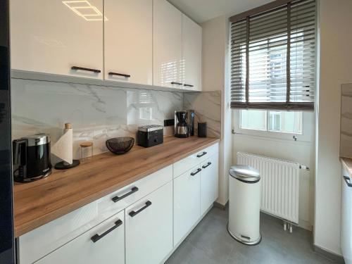 a kitchen with white cabinets and a wooden counter top at Wohnperle*ElbOase*einzigartig*hochwertig*ruhig in Dresden