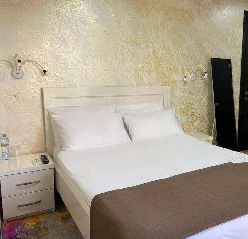 a bedroom with a white bed and a night stand at Hotel Sonata in Batumi