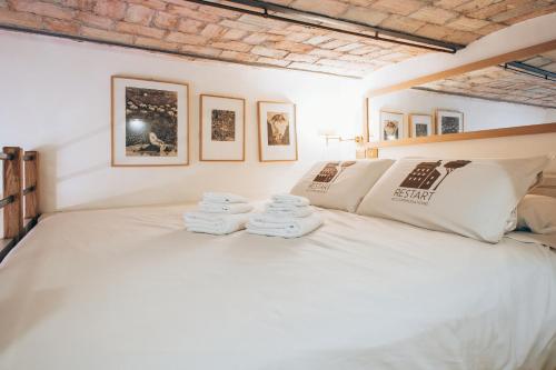 1 dormitorio con 1 cama blanca grande y toallas. en Restart Accommodations Farnesina, en Roma