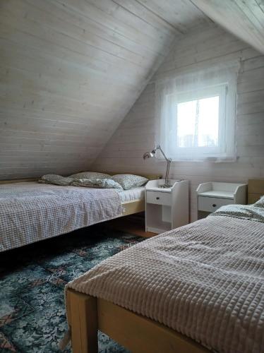 a attic bedroom with two beds and a window at Domki skowronki in Filipów