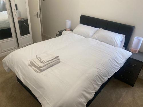 uma cama grande com lençóis brancos e toalhas em Cozy two bedroom flat in the heart of London em Londres