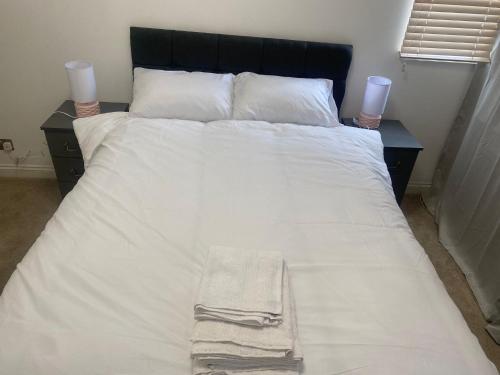 ein großes Bett mit weißer Bettwäsche und zwei Kerzen darauf in der Unterkunft Cozy two bedroom flat in the heart of London in London