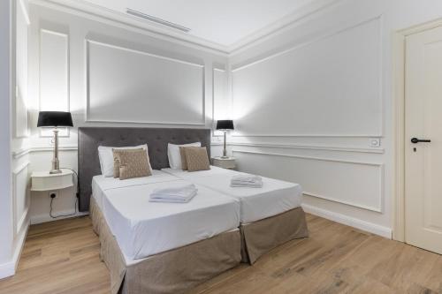 a white bedroom with a large bed and a window at Belle Boutique in Sliema