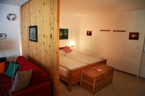 a small bedroom with a bed and a red couch at Rehwiesa in Arosa