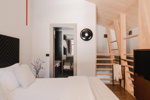 a bedroom with a white bed and a wooden staircase at Aethos Monterosa in Champoluc