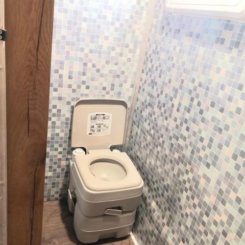 a bathroom with a toilet in a tiled wall at לנפוש על גלגלים in Kefar H̱ananya