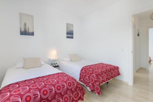 - 2 lits avec des couvertures rouges et blanches dans une chambre dans l'établissement O Nautico Laxe, à Playa Blanca