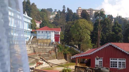 Darjeeling Homestay Nyano Ghar في دارجيلنغ: مجموعة من المباني على تلة مع مبنى احمر