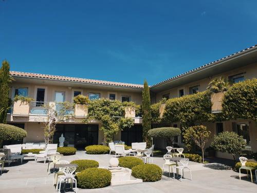 une cour avec des chaises et des tables en face d'un bâtiment dans l'établissement Patio De Violette, à Uzès