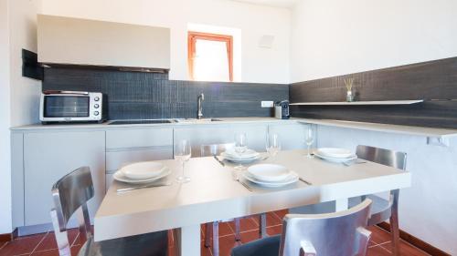 cocina con mesa con sillas y microondas en Welcomely - Petra - Residence Country di Porto Rotondo, en Porto Rotondo