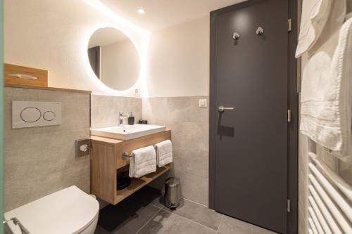 a bathroom with a white toilet and a sink at Hotel Hohe Promenade in Arosa