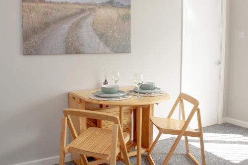a table with two chairs and a painting on the wall at Cosy 3Bed Bungalow in West Kirby, Free Parking in Frankby