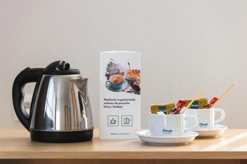 a tea kettle and two cups on a table at Hotel Lechicka in Poznań