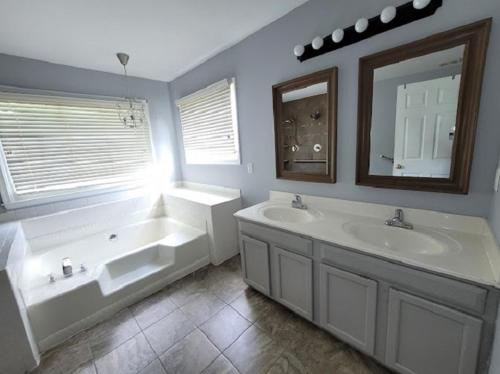 uma casa de banho com 2 lavatórios, uma banheira e um espelho. em Hetten Manor em Woodbridge