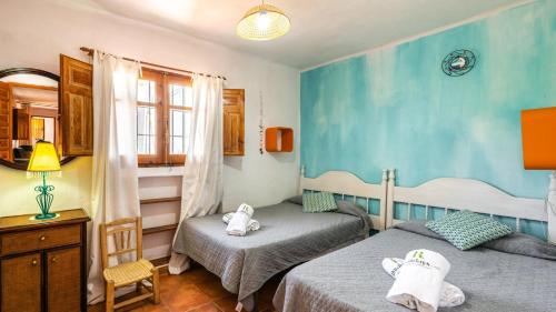 2 Einzelbetten in einem Zimmer mit blauen Wänden in der Unterkunft Cortijo El Nuevo Olivo Órgiva by Ruralidays in Órgiva