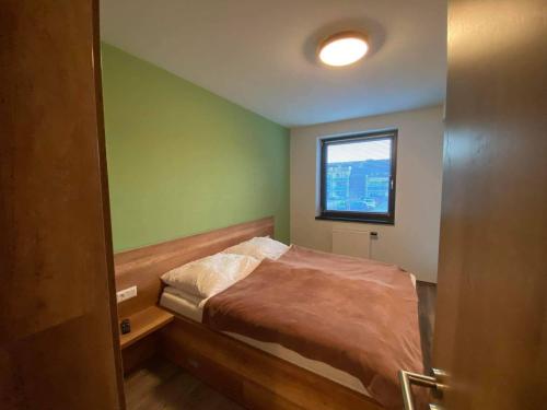 a small bedroom with a bed and a window at Dandelion Apartman in Sárvár