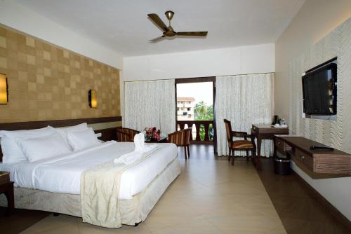 a bedroom with a bed and a table and a television at La Grace Resort in Benaulim