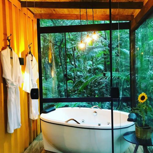 a bath tub in a room with a large window at Pousada Sitio Raizes in Siderópolis
