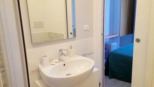baño con lavabo, espejo y cama en Il Piccolo Principe Relais, en Villapiana
