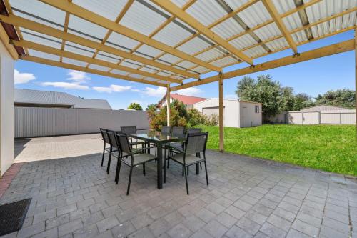 a patio with a table and chairs under a pergola at Swainson on Coombe in Woodville