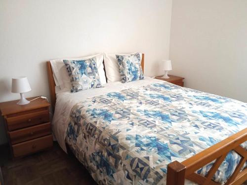 a bedroom with a bed with a blue and white quilt at Baleal Sol Alojamentos in Baleal
