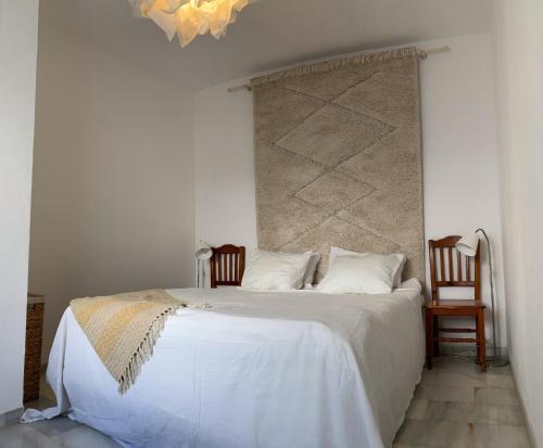 um quarto com uma grande cama branca e 2 cadeiras em Gaviotas em Manilva