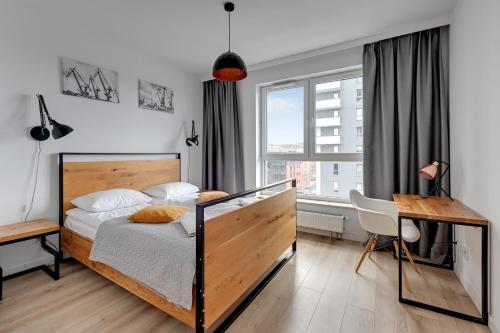a bedroom with a bed and a desk and a window at Bastion Wałowa by Q4Apartments in Gdańsk