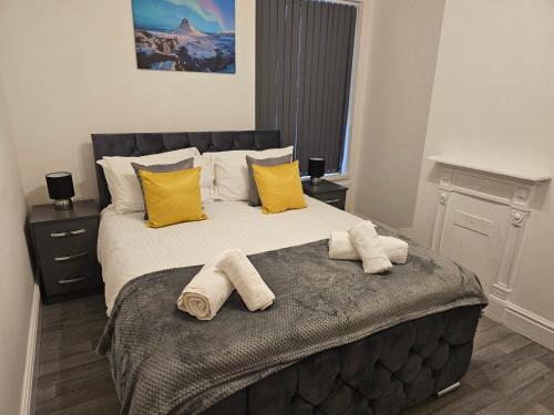 a bedroom with a large bed with towels on it at SAV Apartments - Russell, Luton (4 Bed House) in Luton