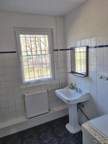 a white bathroom with a sink and a window at FEWO NEUBEEREN in Großbeeren