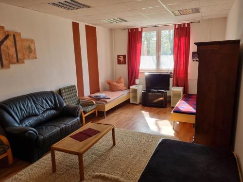 a living room with a leather couch and a tv at FEWO NEUBEEREN in Großbeeren